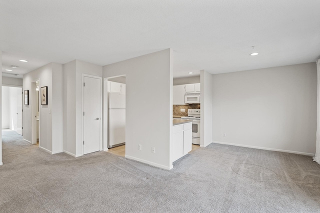 unfurnished living room with baseboards, recessed lighting, and light carpet