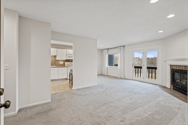unfurnished living room featuring baseboards, recessed lighting, light colored carpet, and a brick fireplace