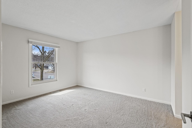 carpeted empty room featuring visible vents and baseboards