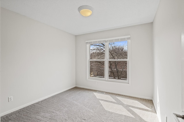 carpeted spare room featuring visible vents and baseboards