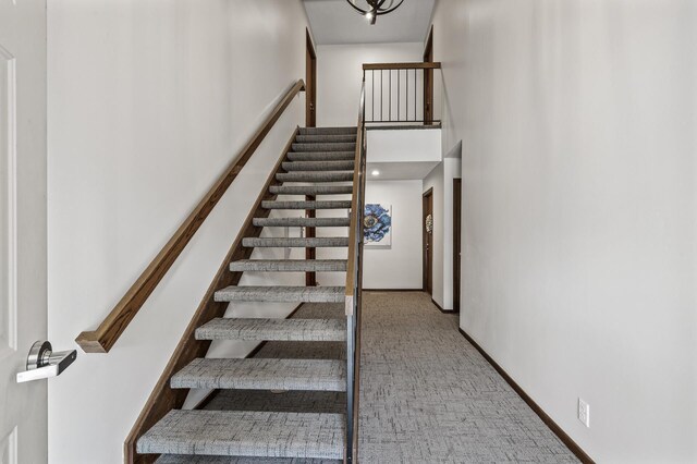 stairway with carpet and a high ceiling