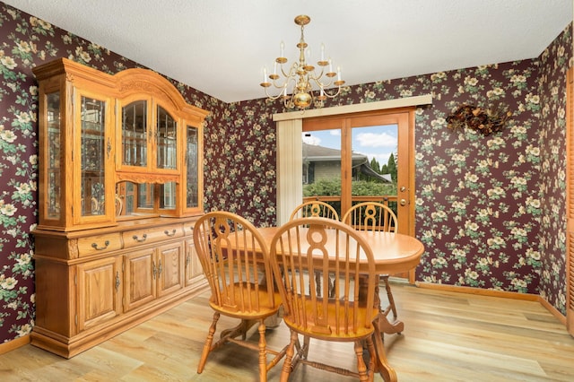 dining space featuring a notable chandelier, light wood-style flooring, wallpapered walls, a textured ceiling, and baseboards