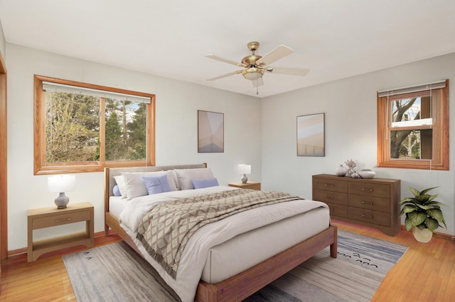 bedroom with light wood-type flooring, baseboards, and ceiling fan