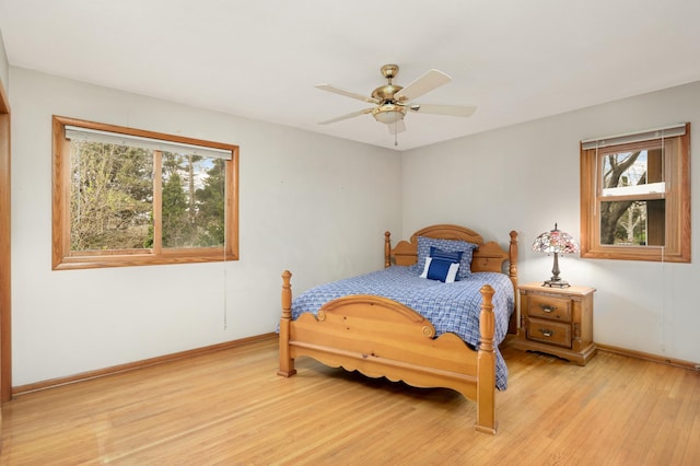 bedroom featuring baseboards, light wood-style floors, and a ceiling fan