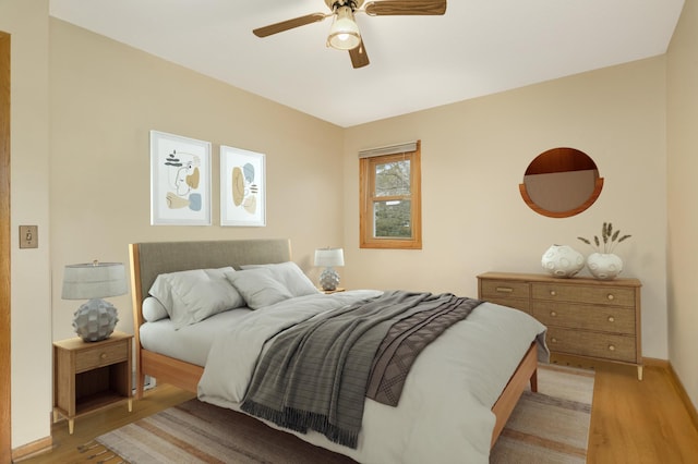 bedroom with ceiling fan, light wood-style flooring, and baseboards