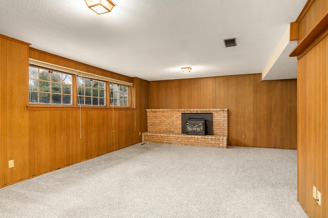 below grade area with carpet flooring, a textured ceiling, visible vents, and wooden walls