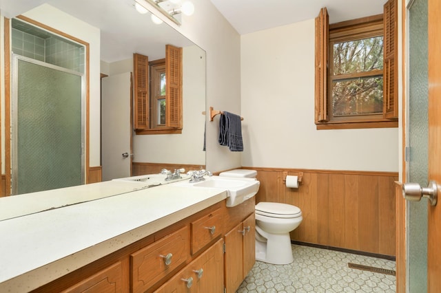 bathroom featuring toilet, wood walls, a shower stall, wainscoting, and vanity