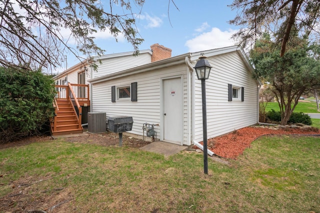 rear view of property featuring a chimney, a yard, stairway, and central air condition unit