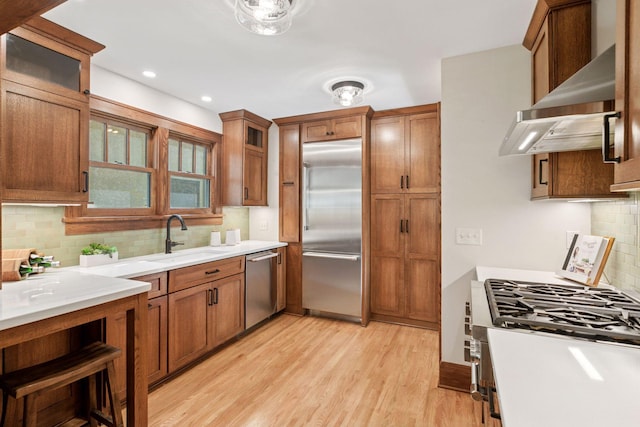 kitchen with stainless steel appliances, a sink, decorative backsplash, light countertops, and recessed lighting