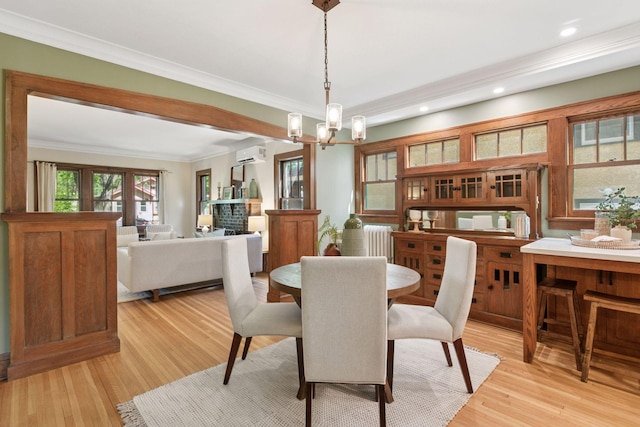 dining area with radiator, a wall mounted air conditioner, a chandelier, crown molding, and light wood-style flooring