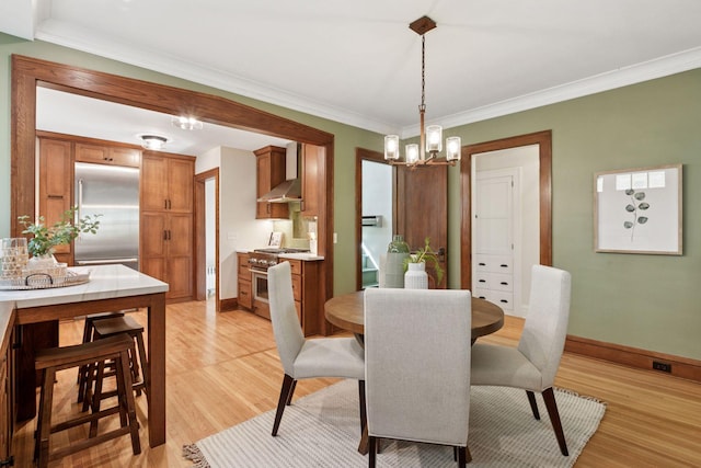 dining area with a chandelier, light wood-style flooring, ornamental molding, and baseboards
