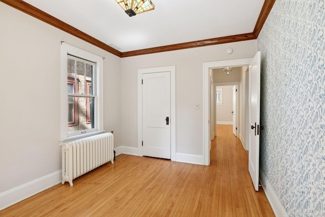 unfurnished bedroom featuring radiator heating unit, wallpapered walls, light wood finished floors, ornamental molding, and baseboards