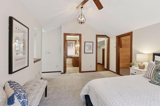 bedroom with light carpet, lofted ceiling, baseboards, connected bathroom, and a walk in closet