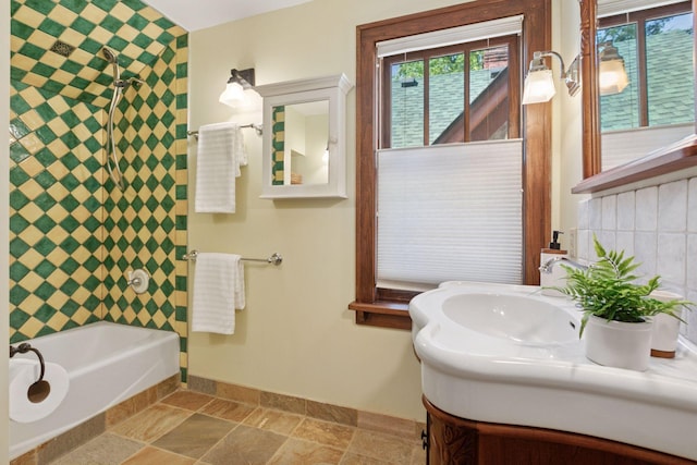 full bathroom featuring baseboards, plenty of natural light, vanity, and stone finish flooring