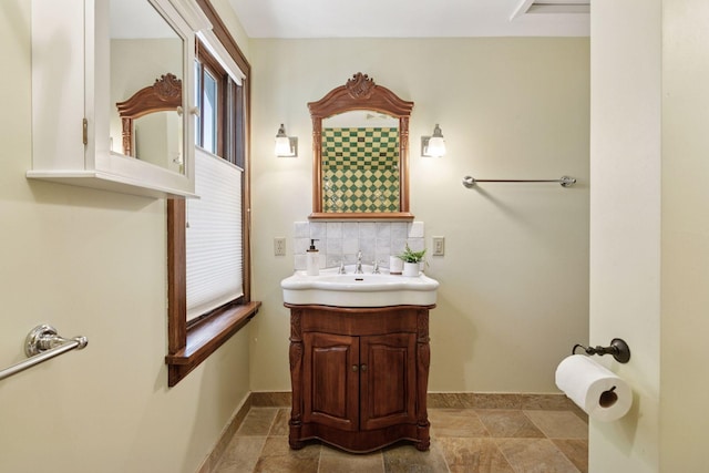 bathroom with tasteful backsplash, vanity, and baseboards