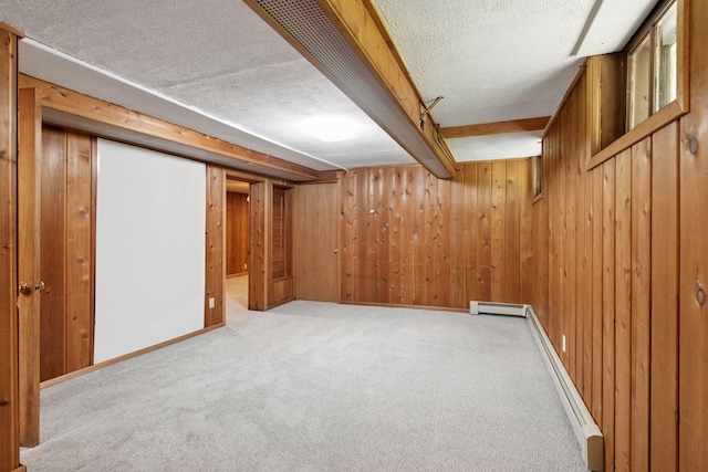 finished below grade area featuring a textured ceiling, carpet floors, wood walls, a baseboard heating unit, and baseboards