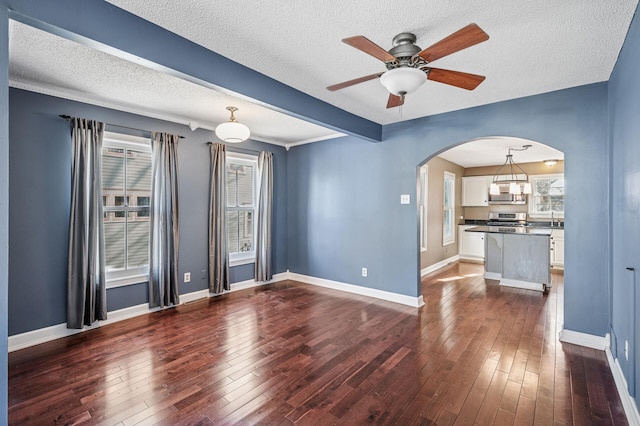 919 6th Ave S, Stillwater, MN 55082 - unfurnished living room featuring arched walkways, a textured ceiling, dark wood-style floors, and a ceiling fan
