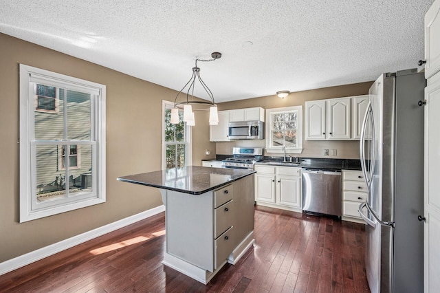 919 6th Ave S, Stillwater, MN 55082 - kitchen with appliances with stainless steel finishes, dark countertops, dark wood finished floors, a textured ceiling, and white cabinets