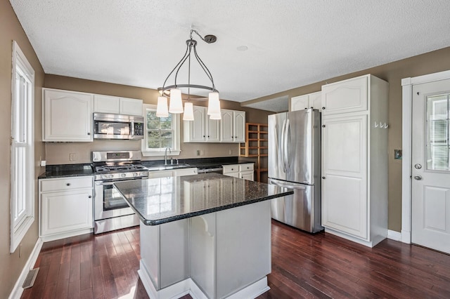 919 6th Ave S, Stillwater, MN 55082 - kitchen featuring stainless steel appliances, white cabinetry, dark wood-type flooring, a kitchen island, and a textured ceiling