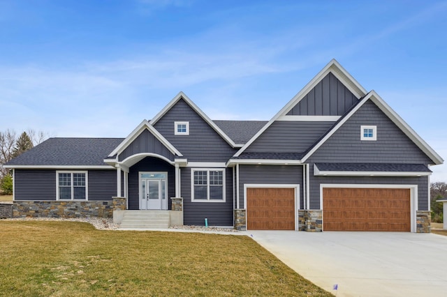 craftsman house with board and batten siding, a front lawn, stone siding, and concrete driveway