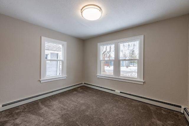carpeted empty room with baseboard heating
