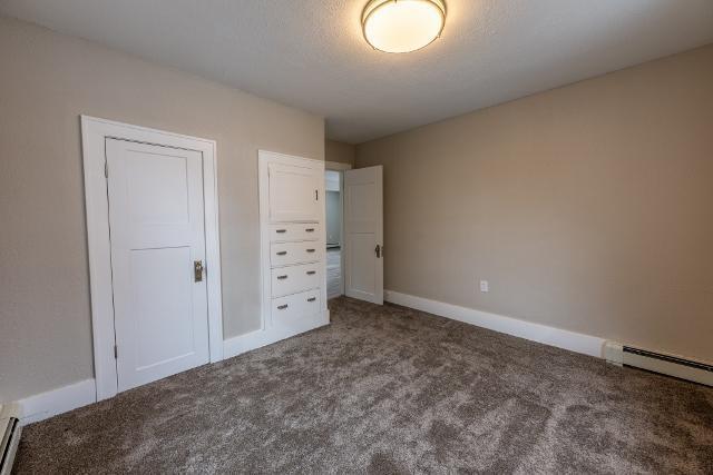 unfurnished bedroom with baseboards, carpet flooring, a baseboard heating unit, and baseboard heating