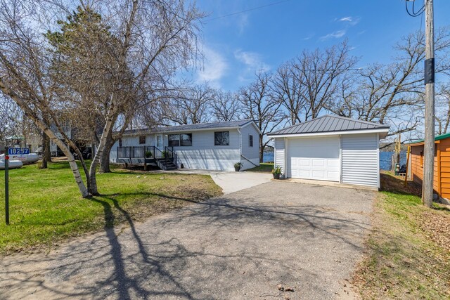 ranch-style home featuring a garage, an outbuilding, driveway, and a front yard