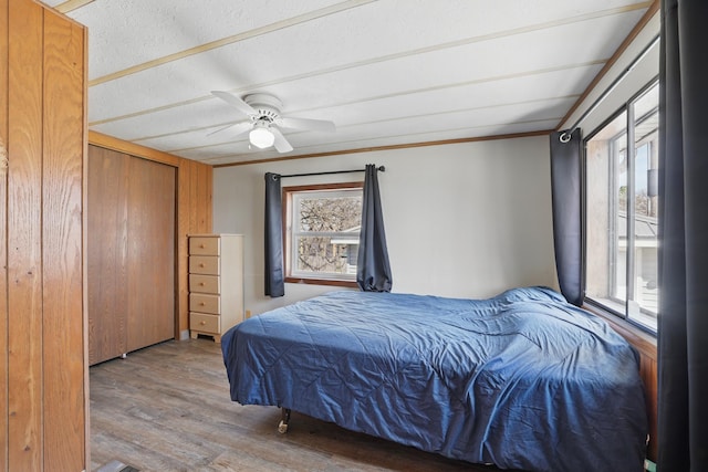 bedroom with ceiling fan, multiple windows, wood finished floors, and ornamental molding