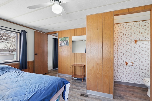 bedroom with visible vents, wood walls, and wood finished floors