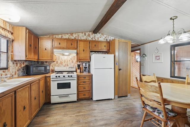 kitchen with plenty of natural light, brown cabinetry, a sink, under cabinet range hood, and white appliances