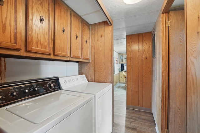 laundry room with separate washer and dryer, wood walls, cabinet space, and wood finished floors