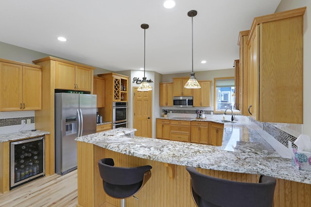 27130 Hickory Ridge Dr, Elko New Market, MN 55020 - kitchen featuring light stone countertops, a peninsula, appliances with stainless steel finishes, a sink, and beverage cooler