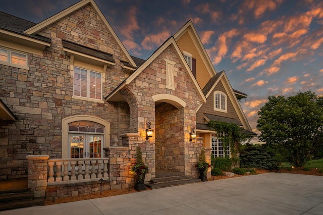 french country home featuring french doors and stone siding