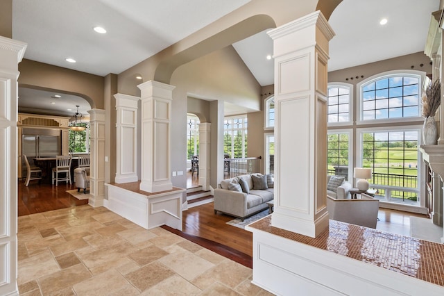living room with ornate columns, recessed lighting, a towering ceiling, and arched walkways