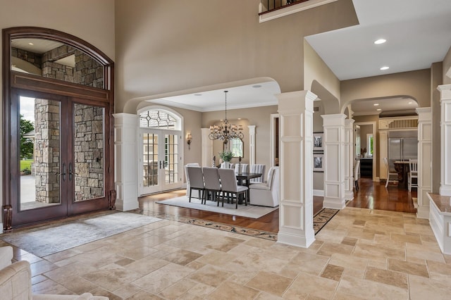 entrance foyer featuring arched walkways, ornate columns, stone tile floors, and a high ceiling