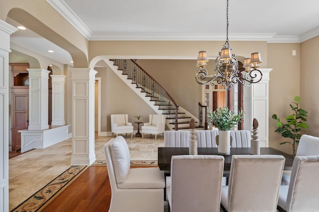dining area with a chandelier, crown molding, ornate columns, and stairway