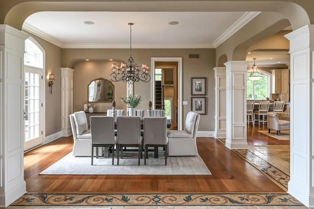 dining room with visible vents, arched walkways, an inviting chandelier, crown molding, and wood finished floors