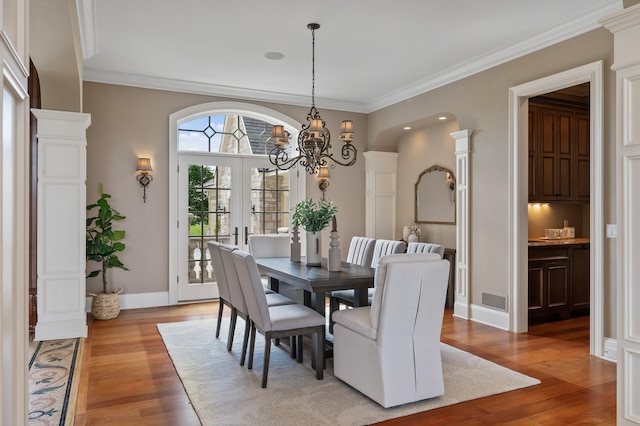 dining room featuring visible vents, a notable chandelier, ornamental molding, light wood-style floors, and french doors
