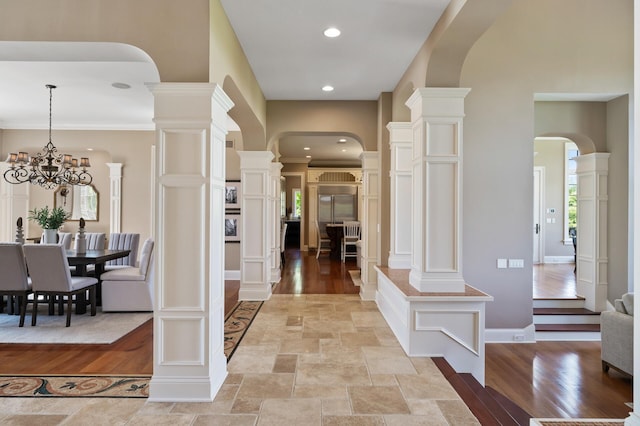 foyer entrance featuring light wood-style flooring, arched walkways, an inviting chandelier, and baseboards