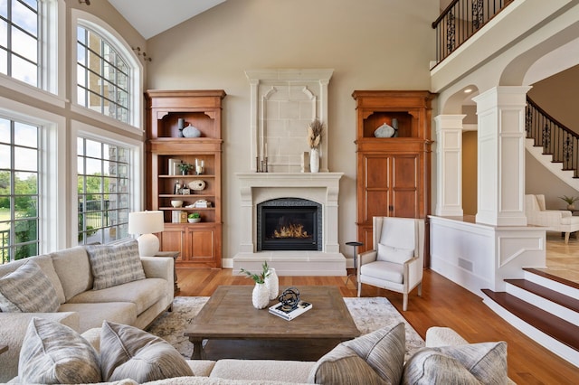 living area featuring high vaulted ceiling, a fireplace, and ornate columns