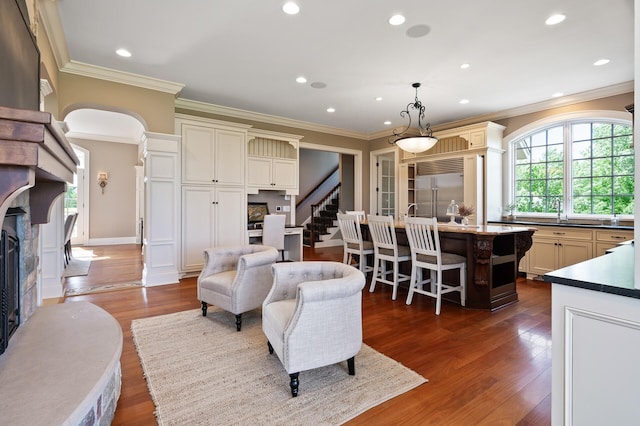 living area featuring ornamental molding, dark wood finished floors, recessed lighting, stairway, and a premium fireplace
