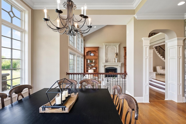 dining area with ornamental molding, stairs, high vaulted ceiling, arched walkways, and wood finished floors