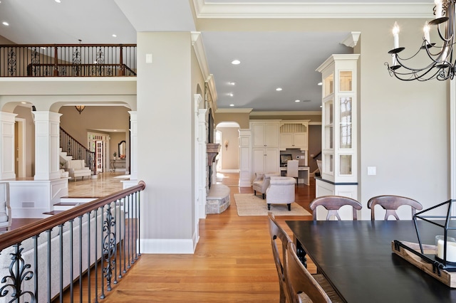 interior space with recessed lighting, light wood-style floors, ornamental molding, and glass insert cabinets