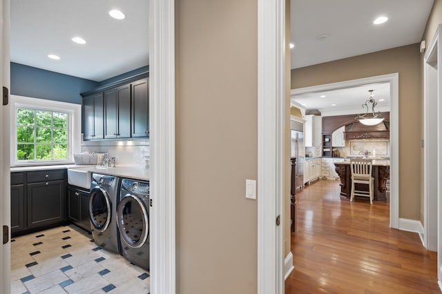 laundry room featuring recessed lighting, washer and clothes dryer, a sink, and cabinet space