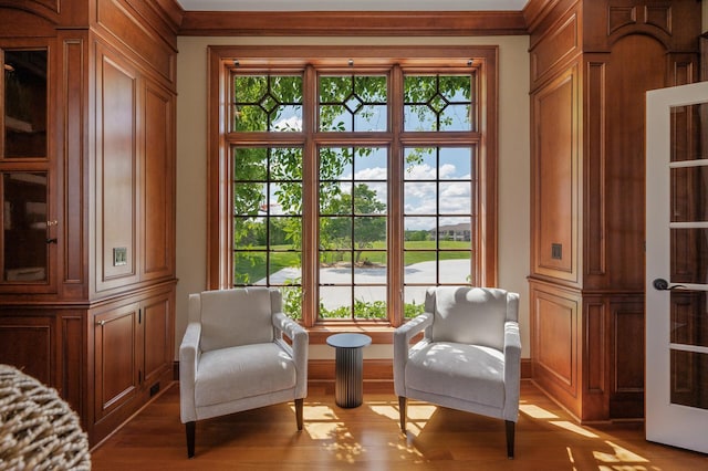 sitting room featuring light wood-style floors, baseboards, and ornamental molding
