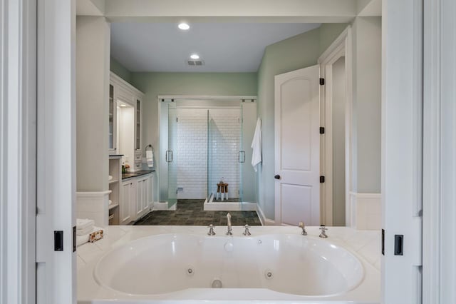 full bathroom featuring visible vents, a shower stall, a tub with jets, and vanity