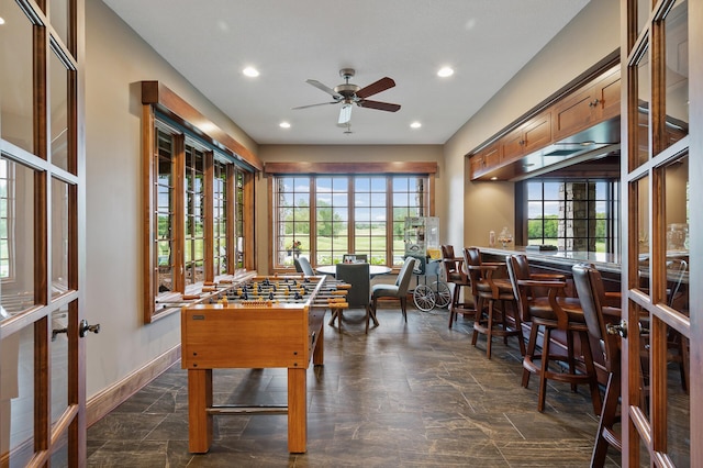 playroom with ceiling fan, recessed lighting, a bar, baseboards, and stone tile flooring