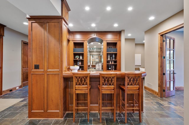 bar with stone tile flooring, a dry bar, recessed lighting, and baseboards