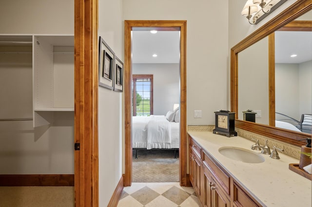 ensuite bathroom with vanity, baseboards, recessed lighting, and connected bathroom