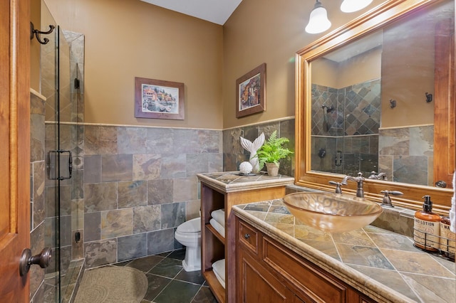 bathroom featuring toilet, vanity, tile walls, and a stall shower
